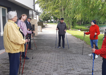 Zdjęcie przedstawia uczestników Klubu Seniora podczas zajęć nordic walking