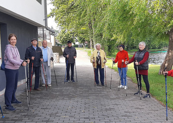 Zdjęcie przedstawia uczestników Klubu Seniora podczas zajęć nordic walking