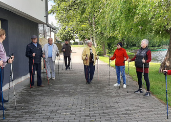 Zdjęcie przedstawia uczestników Klubu Seniora podczas zajęć nordic walking