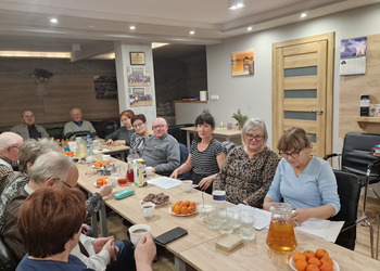 Zdjęcie przedstawia Seniorów zasiadających przy stole