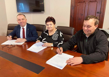 zdjęcie przedstawia trzy osoby podpisujące umowy
