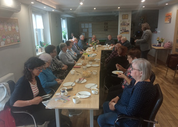 zdjęcie przedstawia seniorów podczas spotkania z antykwariuszem 