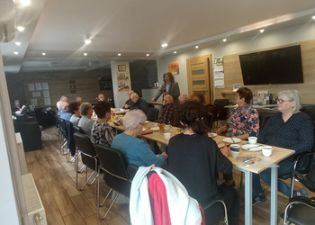 zdjęcie przedstawia seniorów podczas spotkania z antykwariuszem 