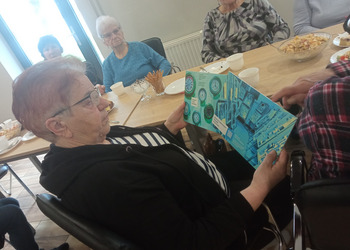 zdjęcie przedstawia seniorów podczas spotkania z antykwariuszem 