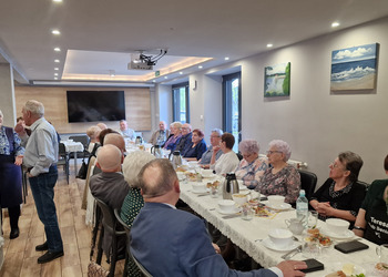 zdjęcie przedstawia seniorów zasiadających przy stole 