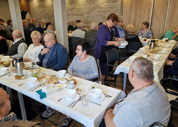 zdjęcie przedstawia seniorów zasiadających przy stole 