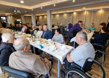 zdjęcie przedstawia seniorów zasiadających przy stole 