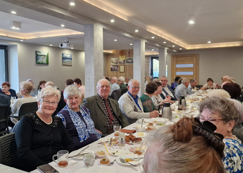 zdjęcie przedstawia seniorów zasiadających przy stole 