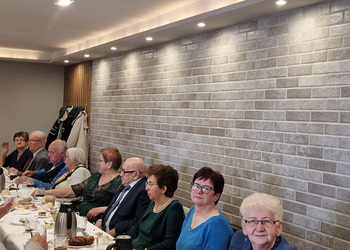 zdjęcie przedstawia seniorów zasiadających przy stole 