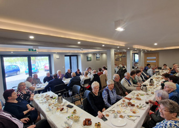 zdjęcie przedstawia seniorów zasiadających przy stole 