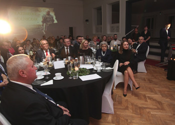 Zdjęcie przedstawia publiczność zasiadającą przy stołach